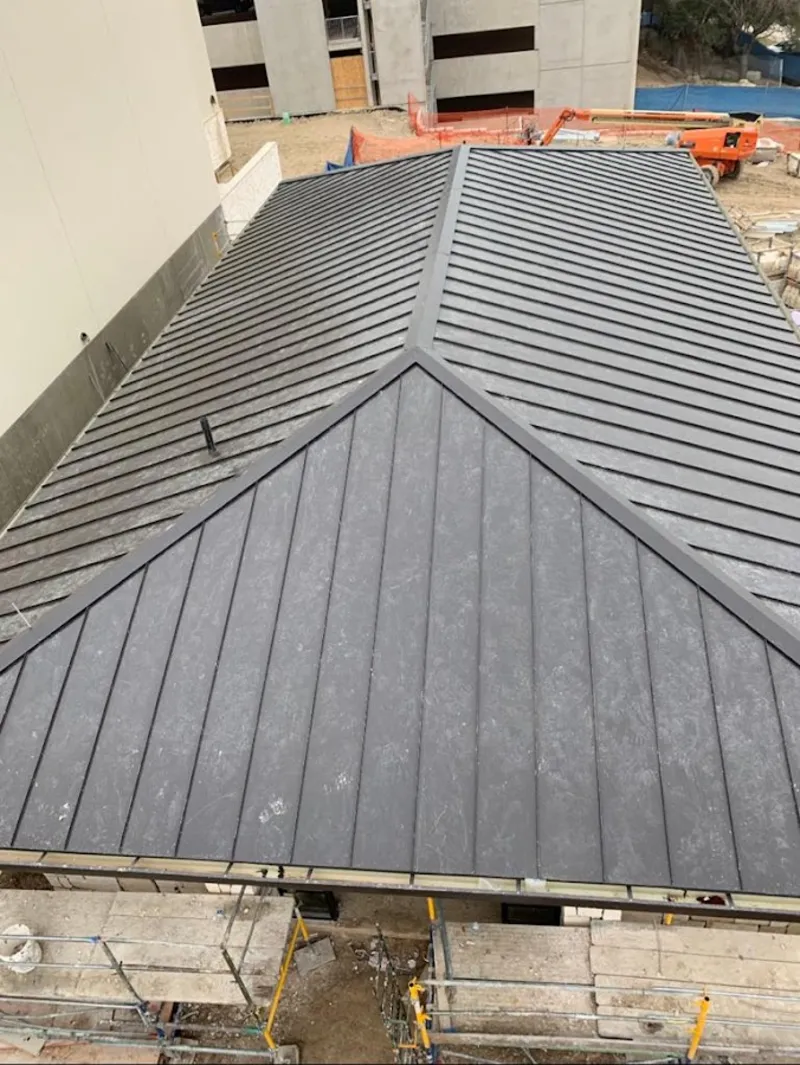 Commercial metal roof construction with crane equipment in Bedford